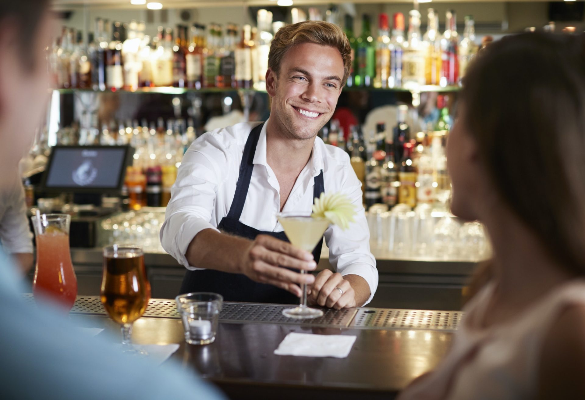 Barman Serving Cocktail To Female Customer In Bar
