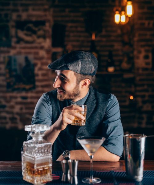 Cheerful bartender enjoying an alcoholic drink at pub, bar or restaurant. Evening relaxation concept